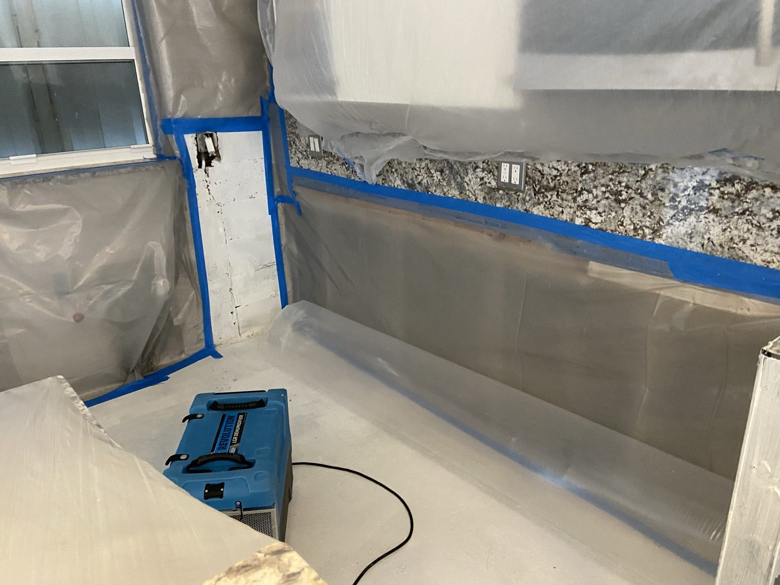 Disaster Recovery Experts containment setup with poly sheeting and a dehumidifier running during structural drying