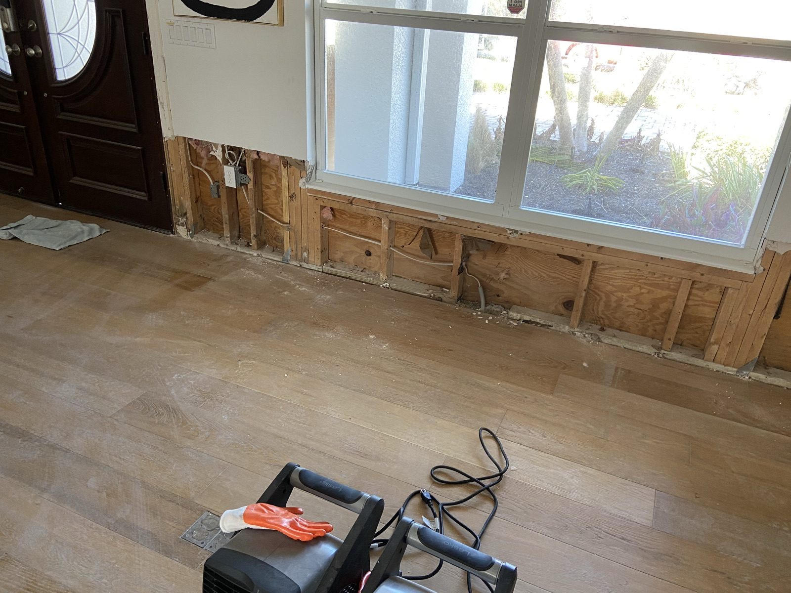 Flood cut along a wall with exposed framing and an air mover running for structural drying