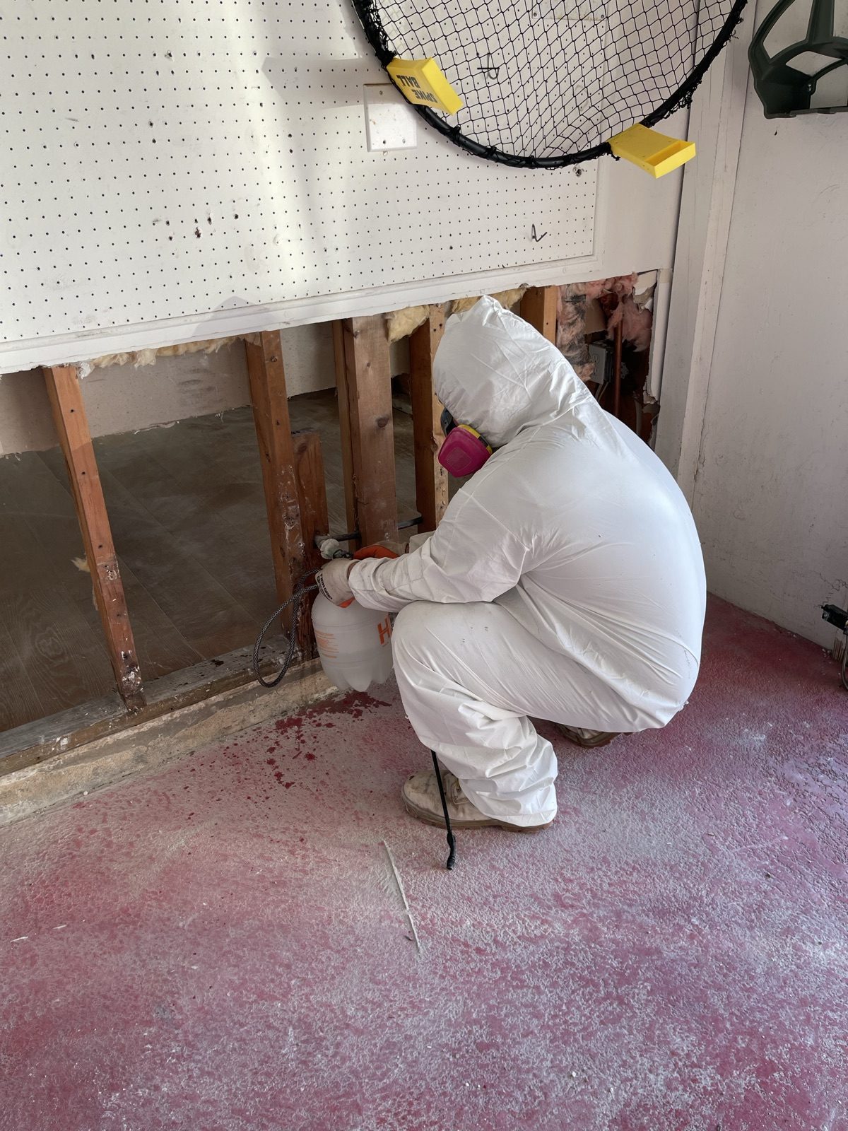 Technician in full PPE removing insulation and performing controlled demolition